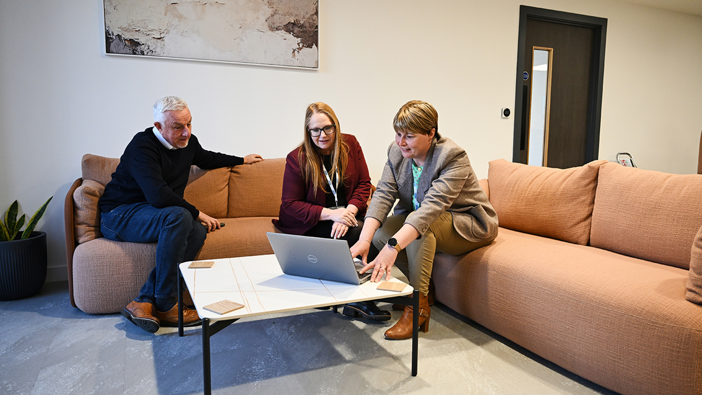 Image of members meeting with staff and working on a laptop
