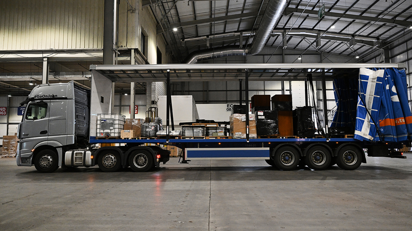 Image of a lorry with the sides peeled back showcasing the load