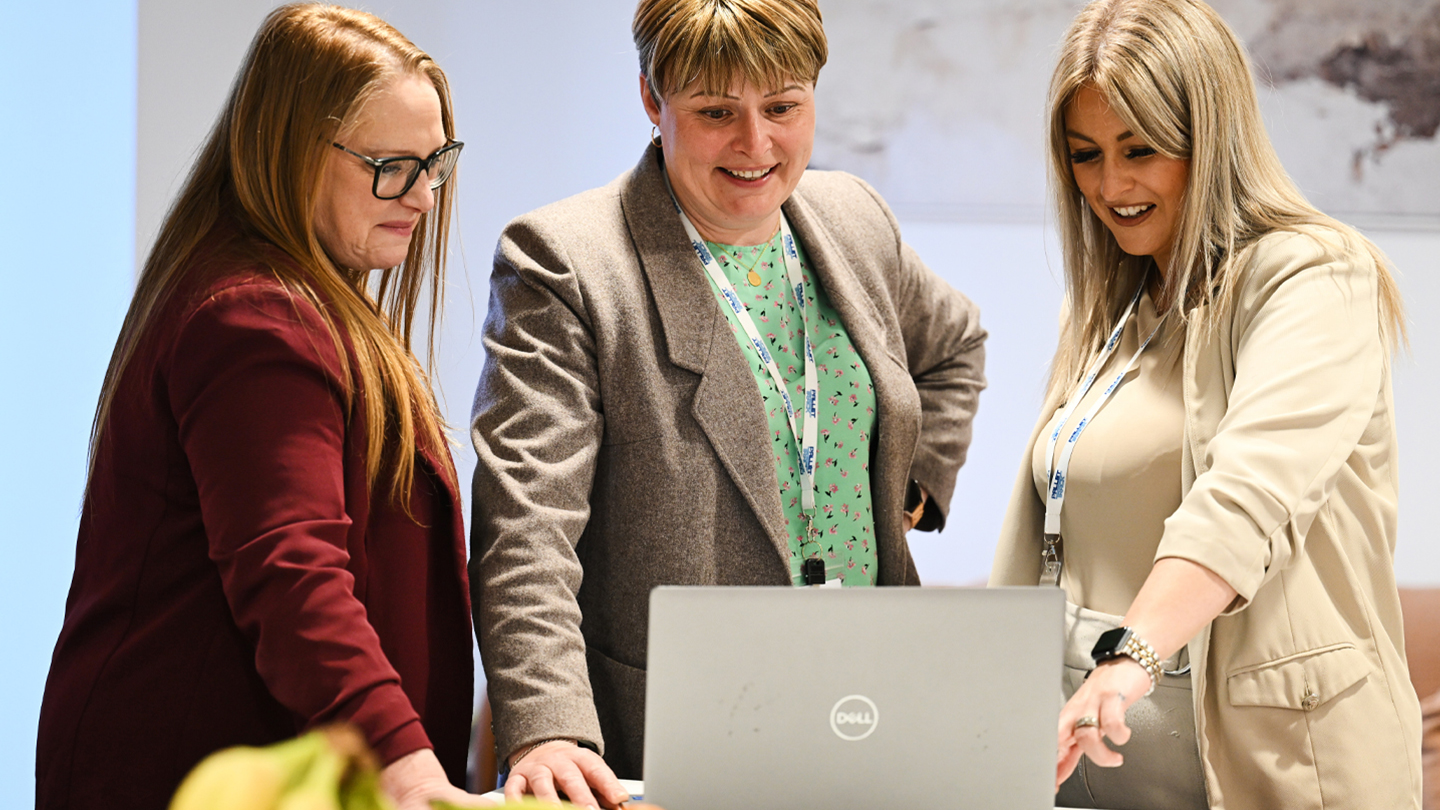 Image of three female employees looking at a laptop