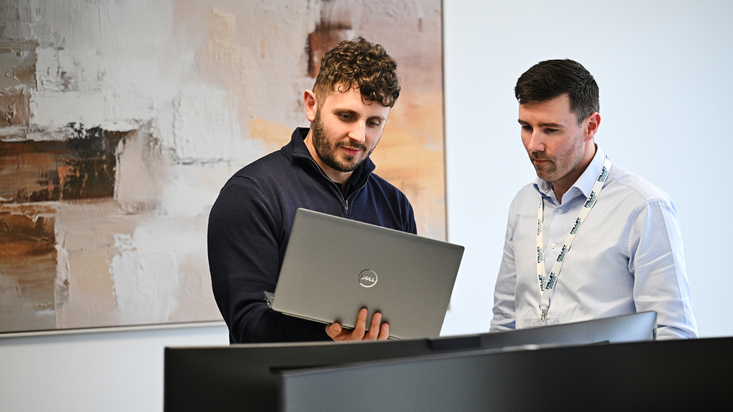 Image of two staff looking at a laptop